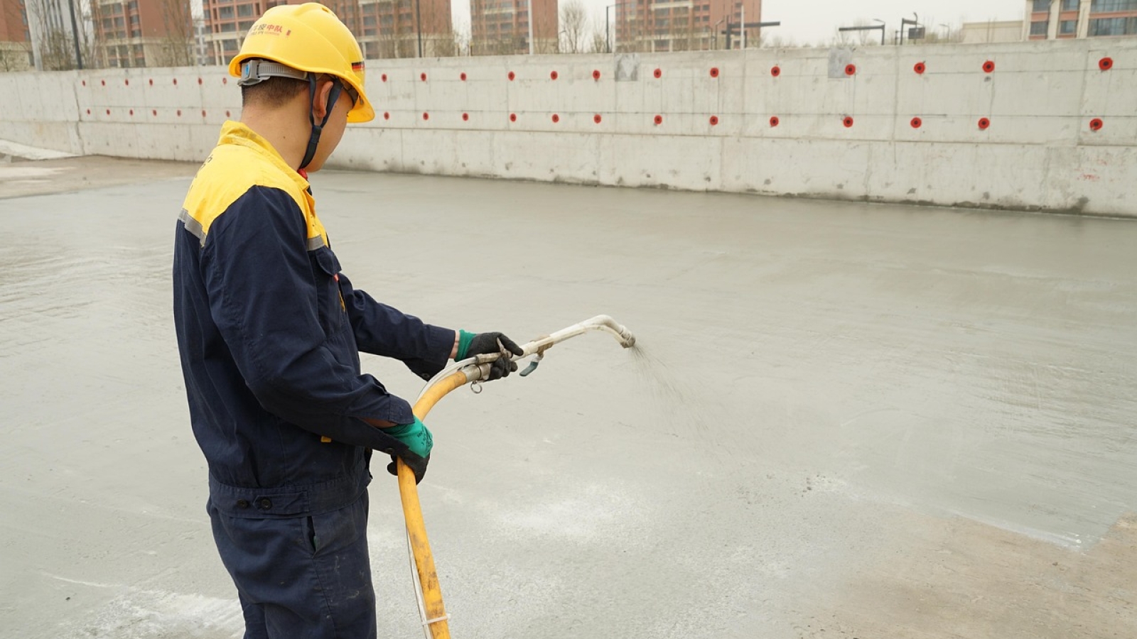 Professional applying waterproofing coating to concrete foundation surface